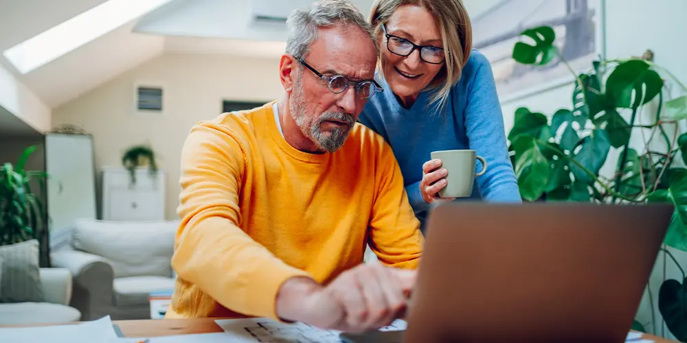 couple looking at their laptop together reading about reasonable rate of returns in retirement
