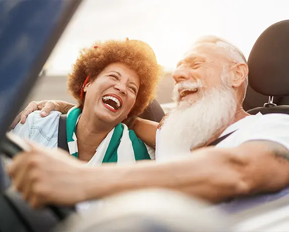happy retired couple driving in their convertible
